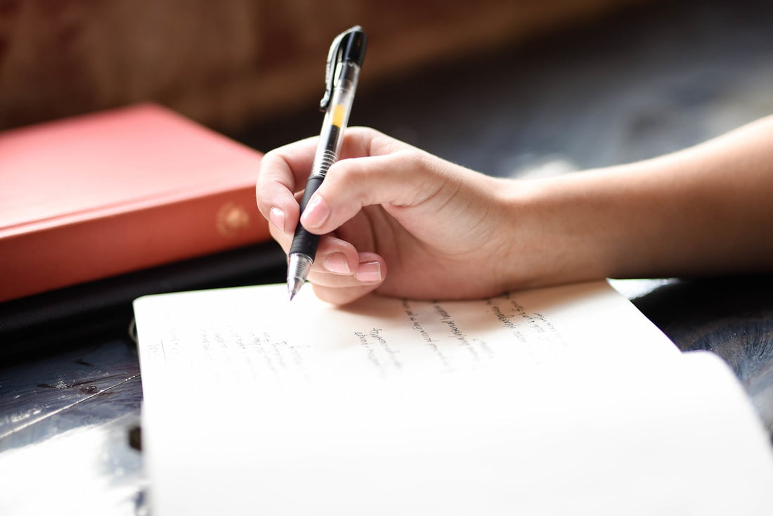 Hand schreibt in ein Notizbuch am Fenster – ein Mitmachbuch zum Selbstgestalten