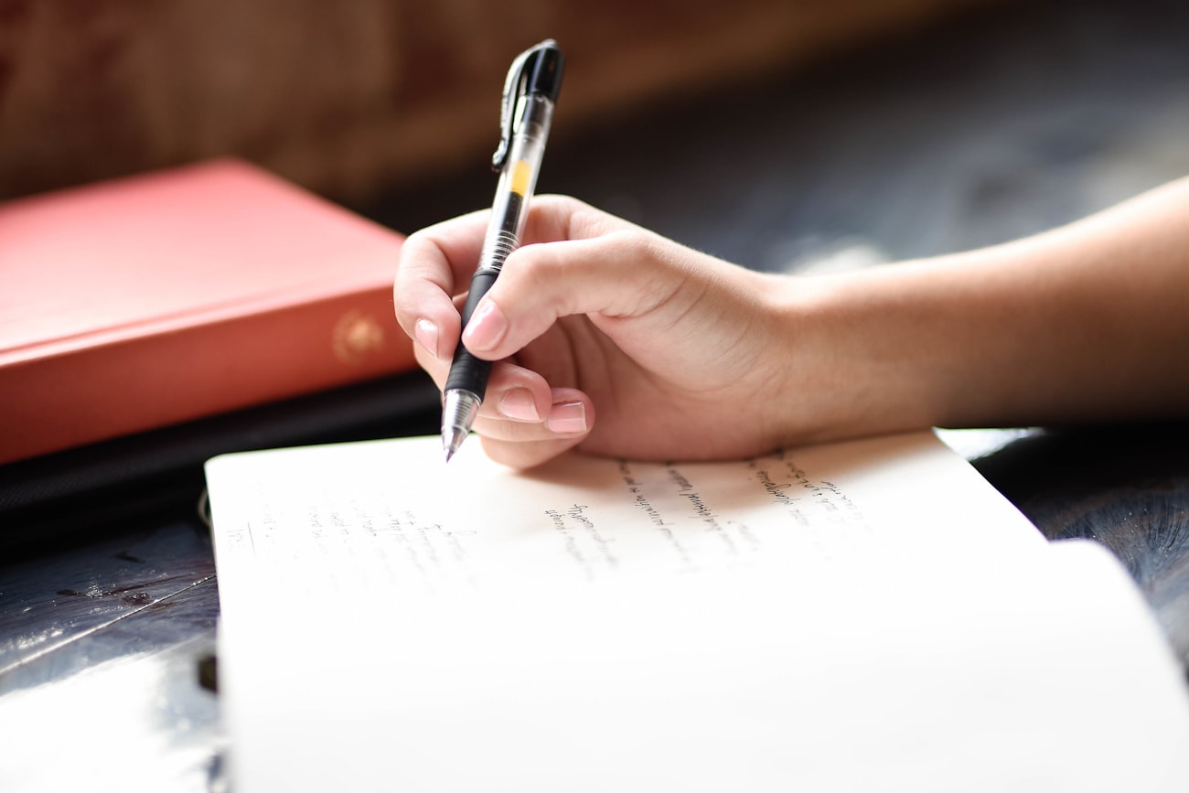 Hand schreibt in ein Notizbuch am Fenster – ein Mitmachbuch zum Selbstgestalten